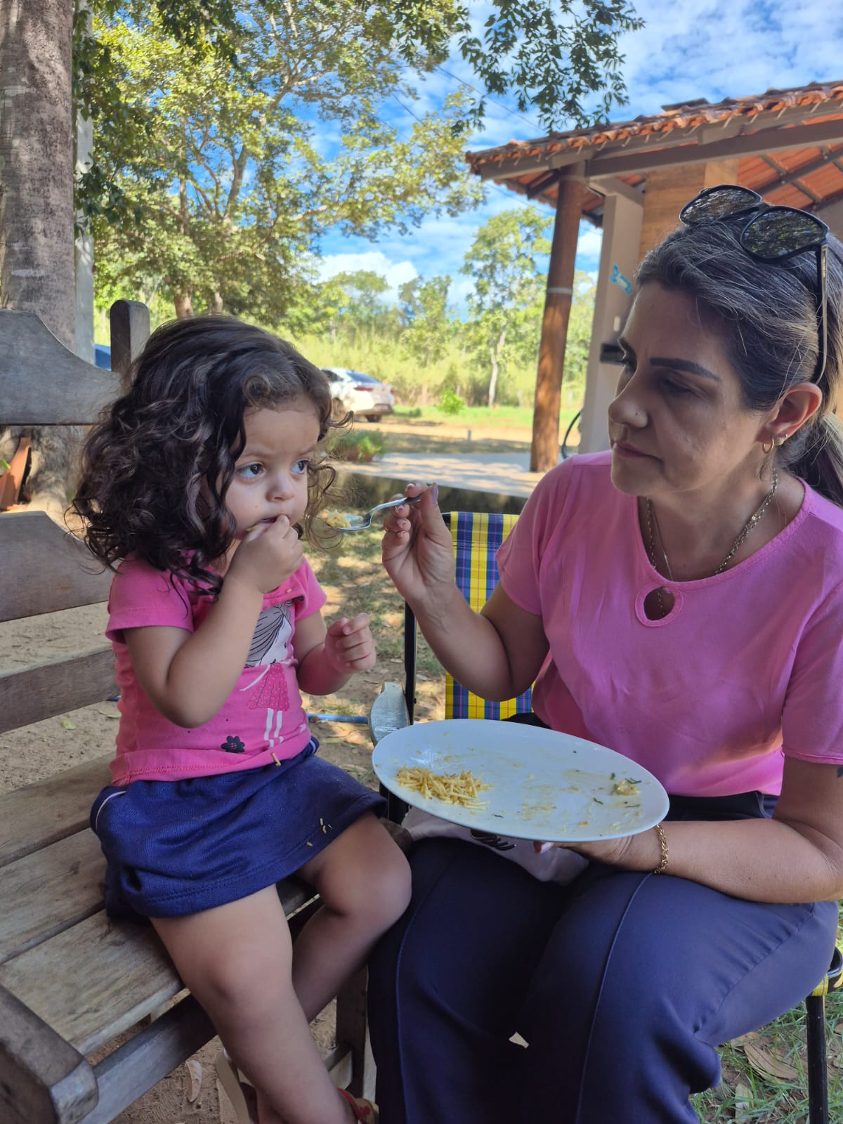 Marlupe oferecendo comida a uma criança sentada ao seu lado