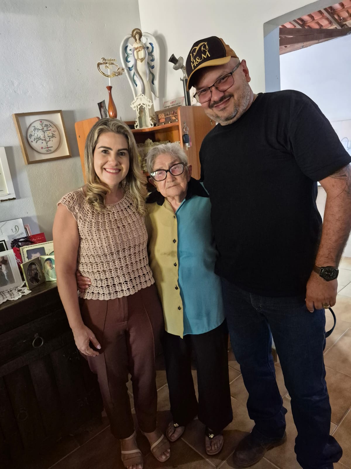 Marlupe com uma mulher mais velha e um homem em uma casa